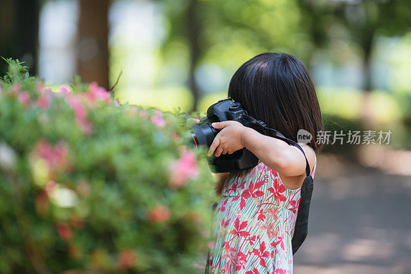 小女孩在公园里拍花的照片