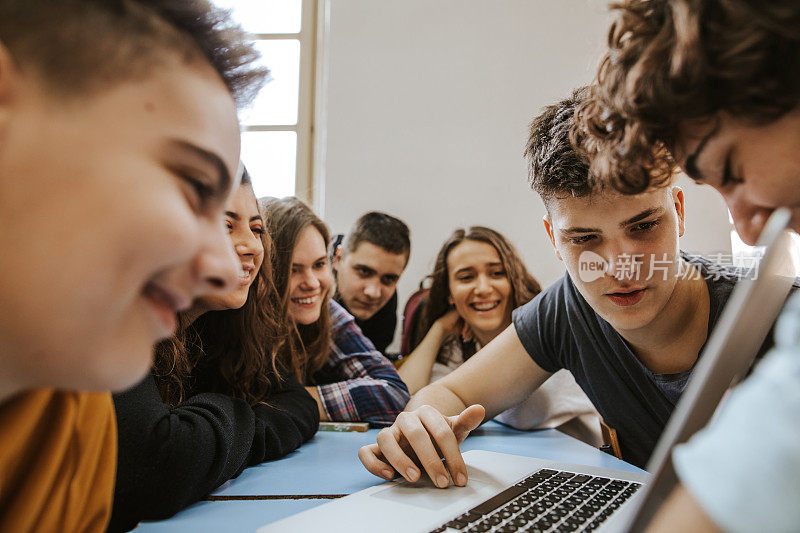 一群青少年在用笔记本电脑聊天和微笑