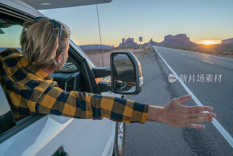 公路旅行概念;年轻人在房车里看着路，手臂伸出窗外;国家公园和大自然为探险做好了准备