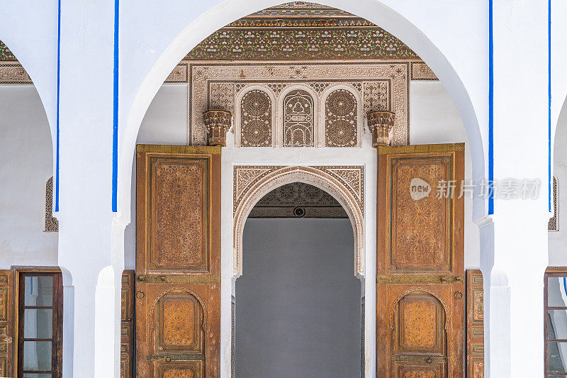 拱门入口有巨大的木门，门上装饰着传统的摩洛哥马赛克和阿拉伯语碑文。马拉喀什古城(麦地那)。