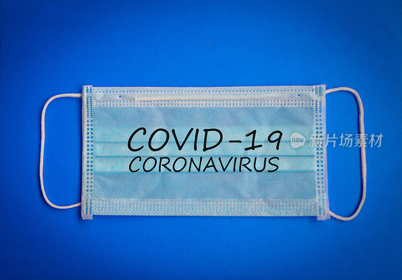 绿色手术防护无菌口罩，以蓝色背景书写COVID-19冠状病毒