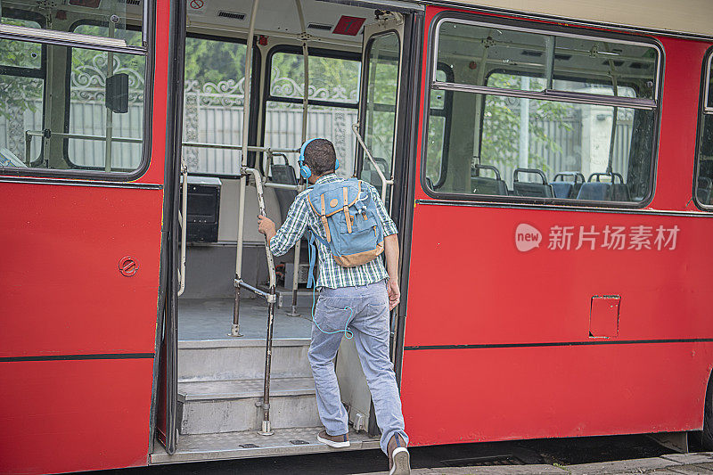 戴着耳机的年轻人正在上公交车