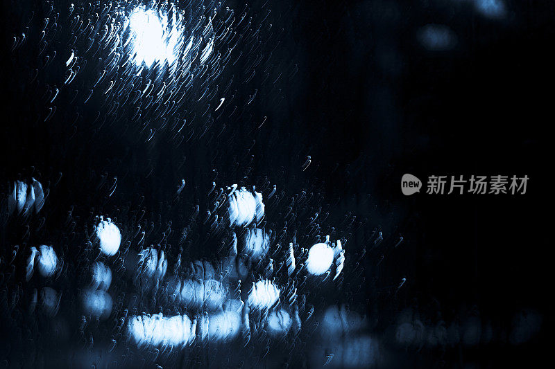 抽象的雨滴落在窗户上，模糊了城市的灯光