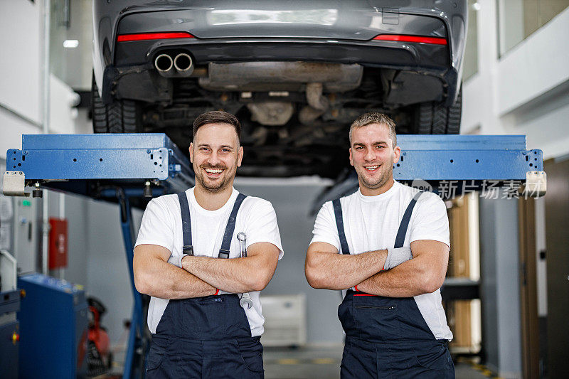 在汽车修理厂，快乐的修理工双臂交叉。