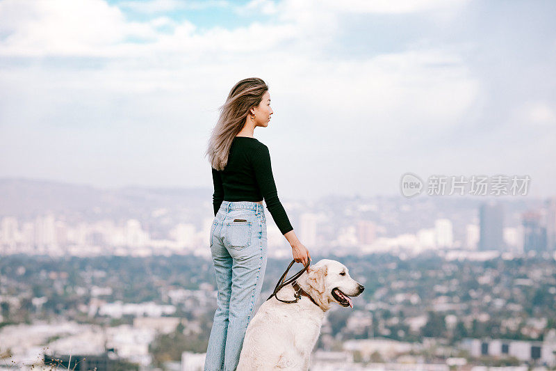 年轻女子与她的狗在加州公园看风景