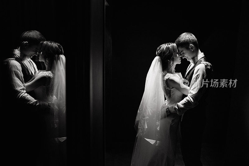 婚纱摄影在反思中的创意摄影创意。新娘和新郎被灯光照亮。