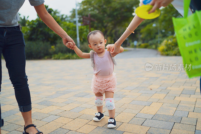 哄一个带护膝的亚洲幼童走出户外的第一步