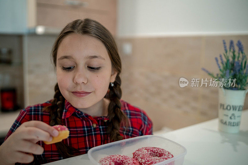 对孩子的饮食。悲伤和不快乐的孩子触及甜甜圈。孩子们的美味食物。孩子在看甜甜圈。垃圾食品上瘾。