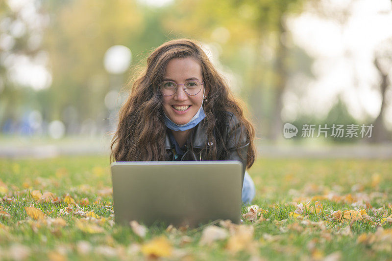 在冠状病毒社会隔离期间在公园工作的妇女。秋天微笑的女人