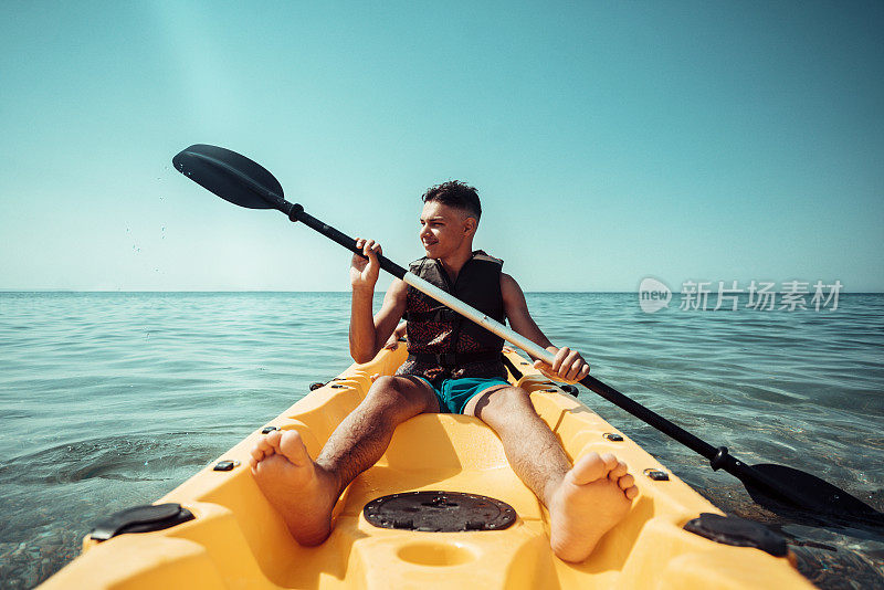 十几岁的男孩在海上划皮艇