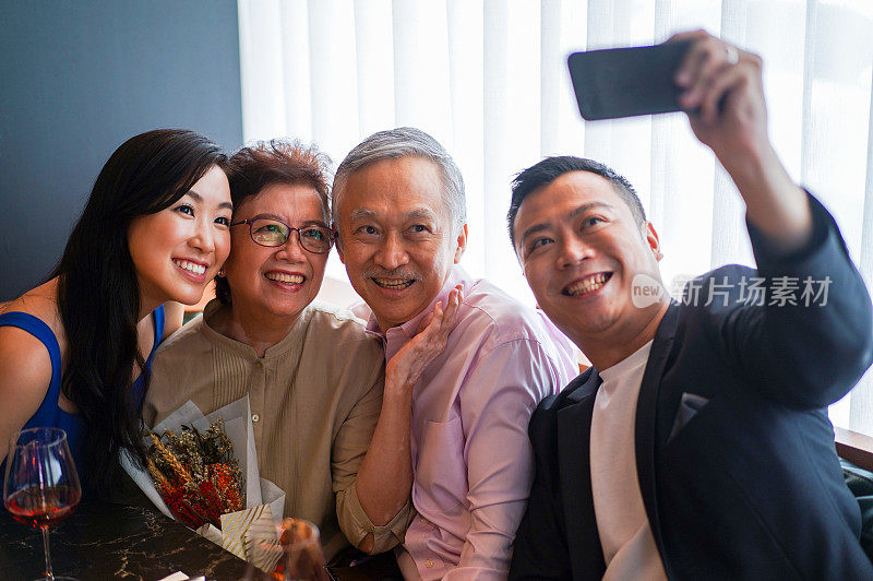 亚洲家庭在餐桌上用手机自拍。