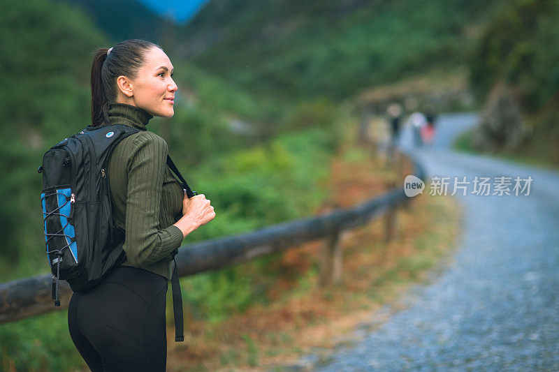 背着背包的年轻女子徒步旅行者在户外的山区旅行