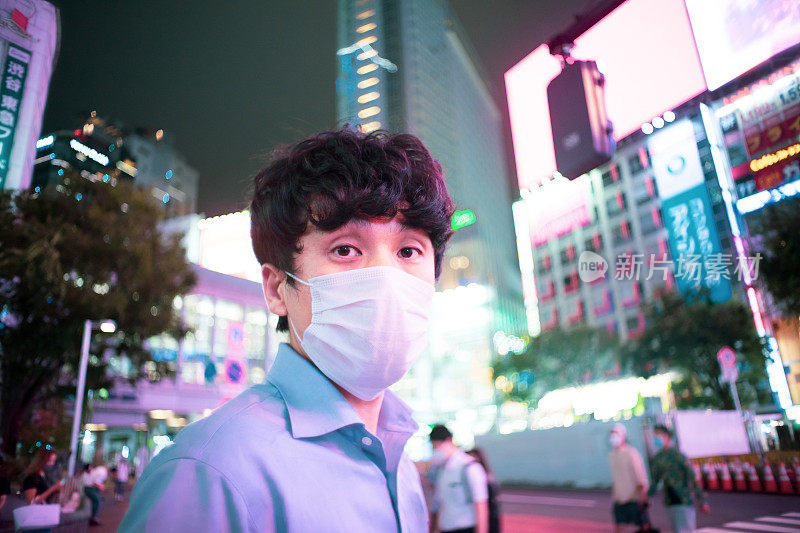 一幅戴着面具的亚洲男子的肖像，展示着城市的夜景