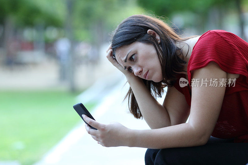 一个可悲的女人在公园里查看手机