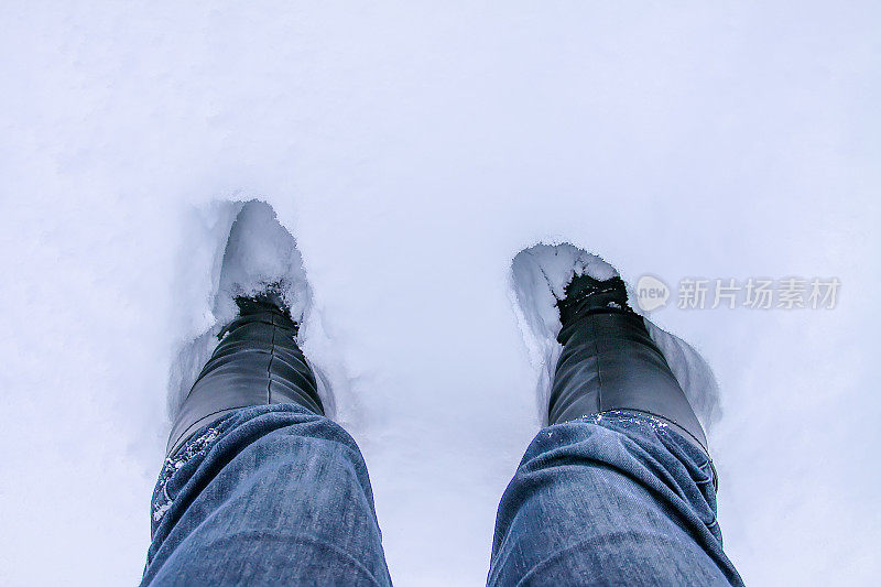 踏在厚厚的雪地里。蓝色牛仔裤的腿在漂移。