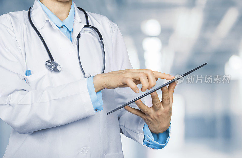 医生在医院背景上触摸平板电脑的屏幕。医疗保健和技术概念。