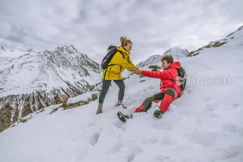 一对年轻的徒步旅行者在白雪皑皑的山脊上嬉戏