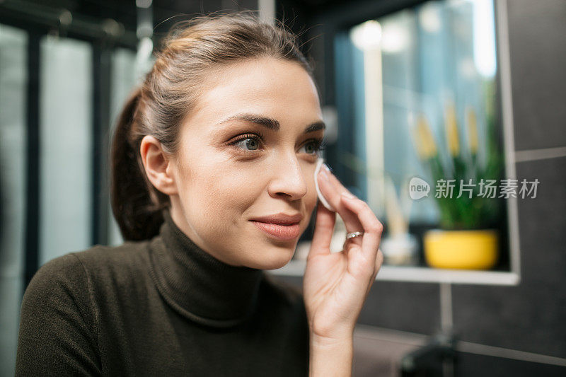 一个快乐的年轻白种女人的特写，用化妆品照顾她的脸