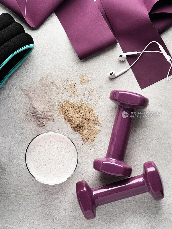 运动配件和蛋白奶昔，女性运动设备的背景，哑铃与巧克力和草莓蛋白粉，摇床粉碎成蛋白粉，