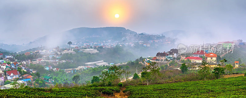 在日出的天空下，一个小村庄的茶山山谷