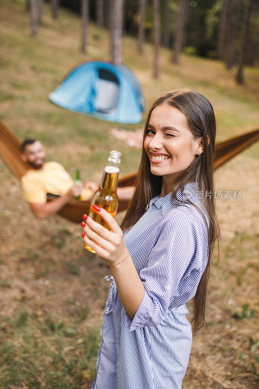 幸福的夫妇露营，有乐趣和喝啤酒的森林