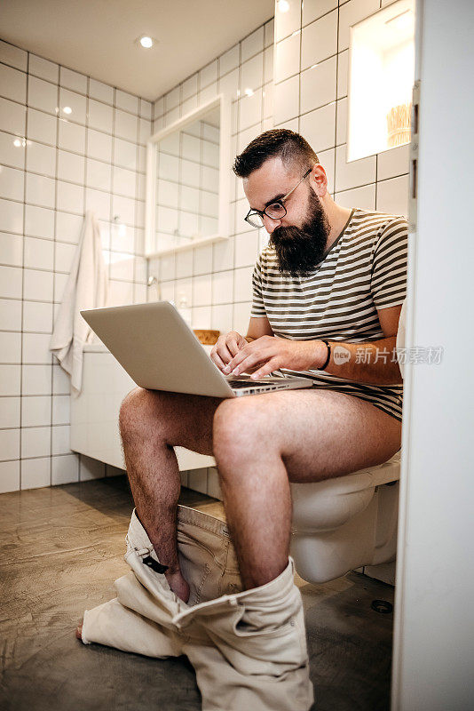 一个年轻人在厕所里用笔记本电脑