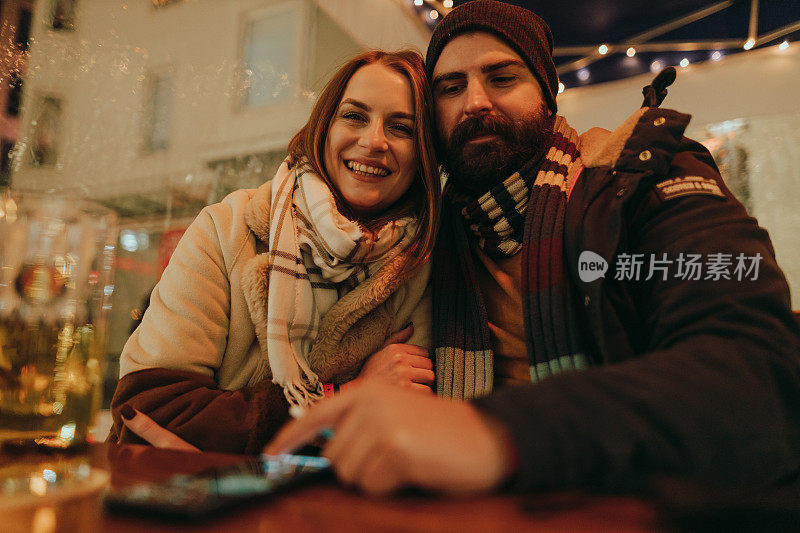 一对相爱的夫妇在冬夜享受圣诞市场