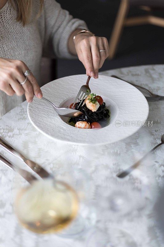 女人吃着黑意大利面和海鲜