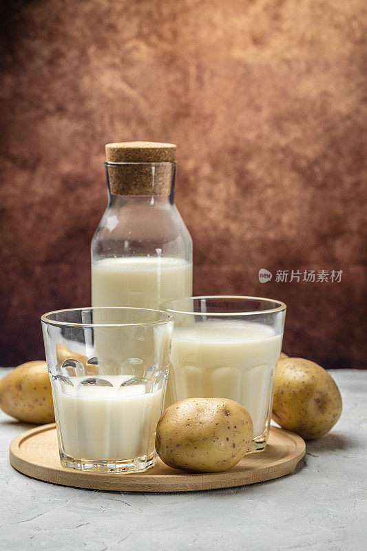 玻璃素食土豆奶和生土豆。替代植物奶。超级食品的概念。健康,干净的吃。素食或无麸质饮食。垂直图像放置文本