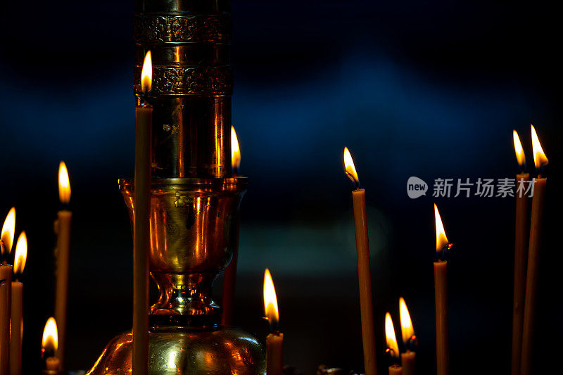 在东正教堂黑暗的内部有许多燃烧的蜡烛的烛台。