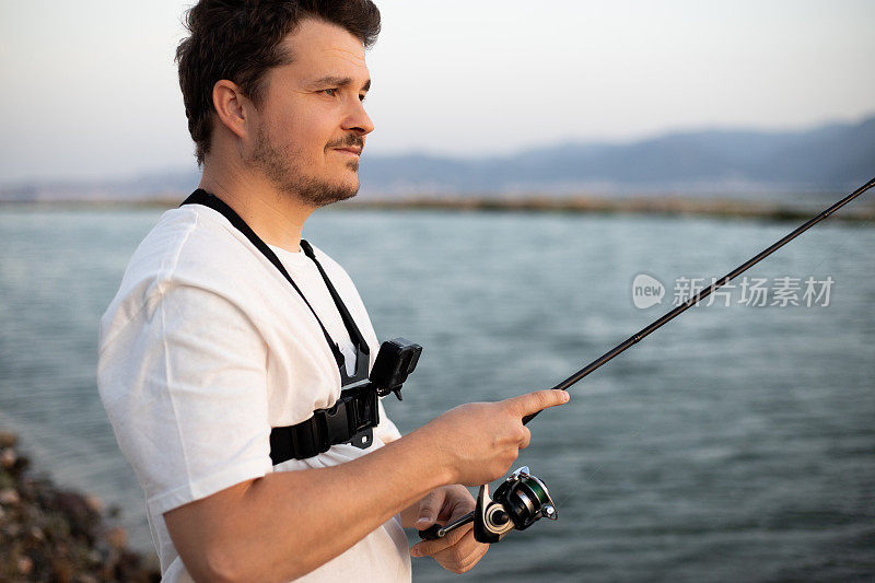 一名男子在钓鱼时用摄像机拍摄视频