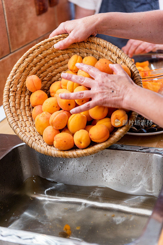 家庭厨房中洗杏自制果酱的两代妇女