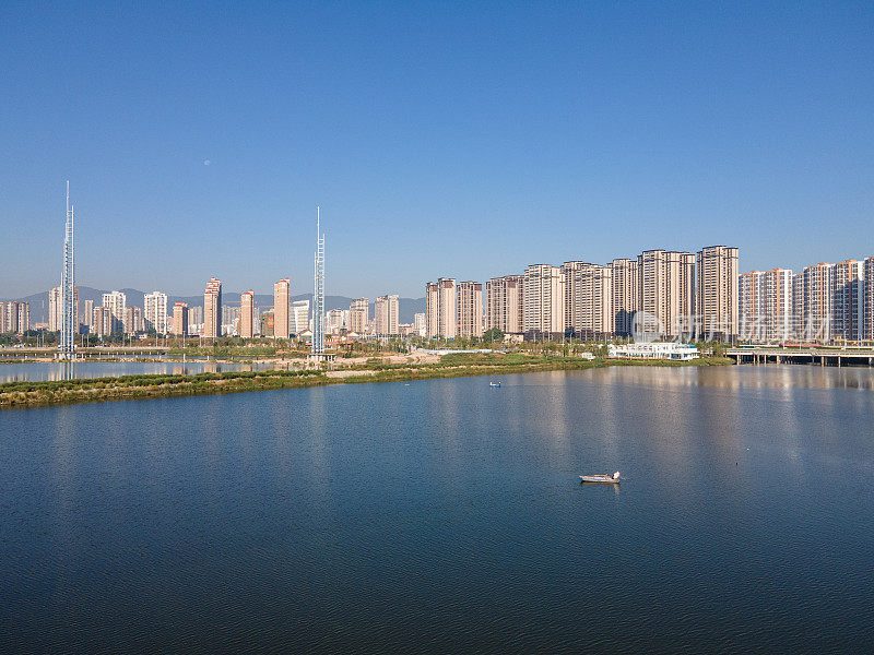 湖面倒映着现代城市建筑和蓝天