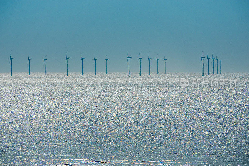现代风力涡轮机一排排地矗立在海上。太阳在水面上的倒影