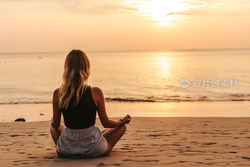 年轻女子在海滩上练习瑜伽