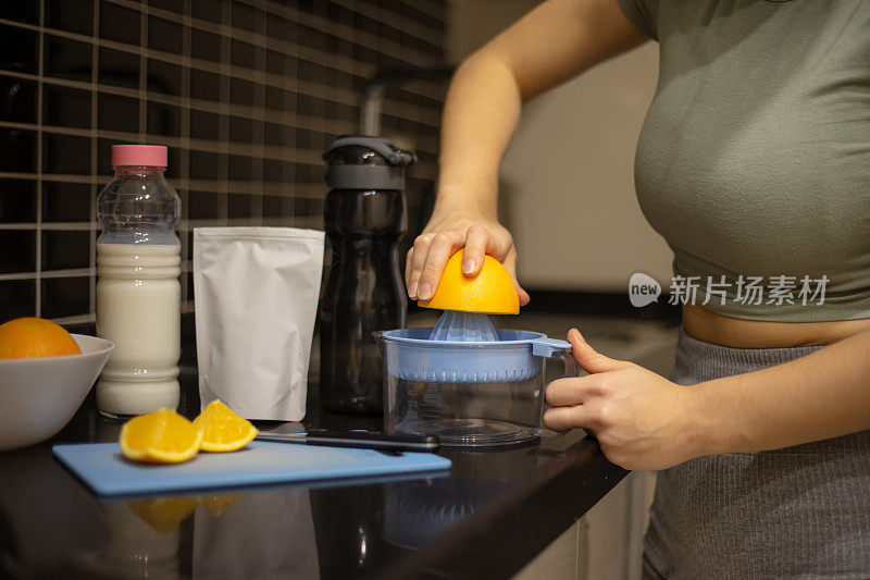 年轻女子在厨房准备运动饮料。