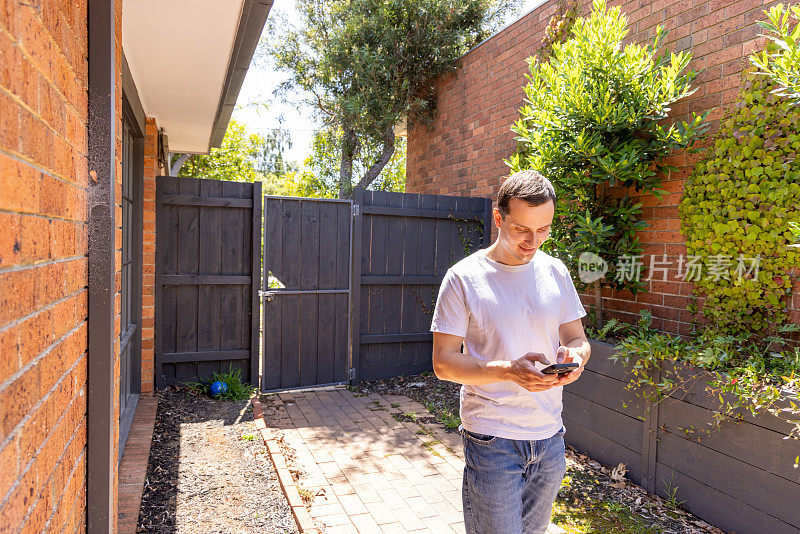 快乐的男人在家使用无线技术，他在户外使用电话