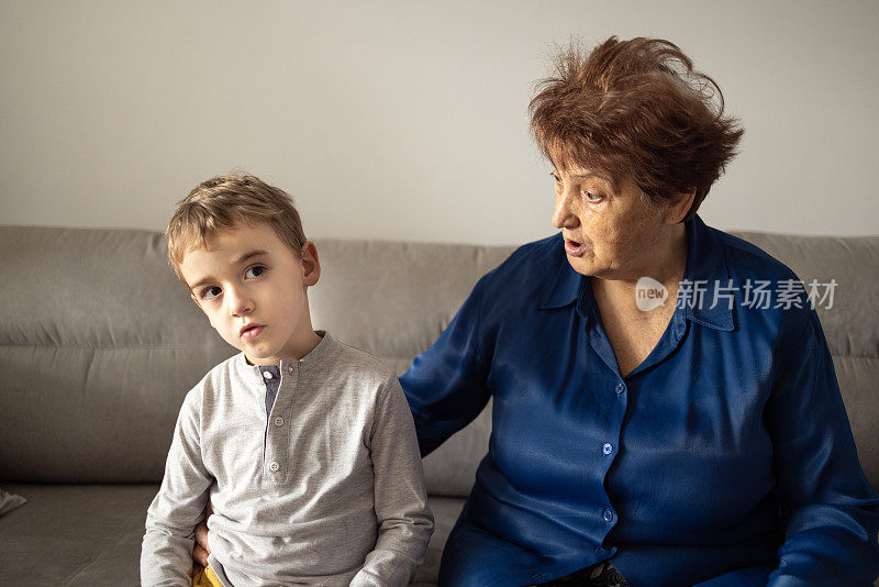 孙子坐在沙发上看电视，奶奶却在责骂他