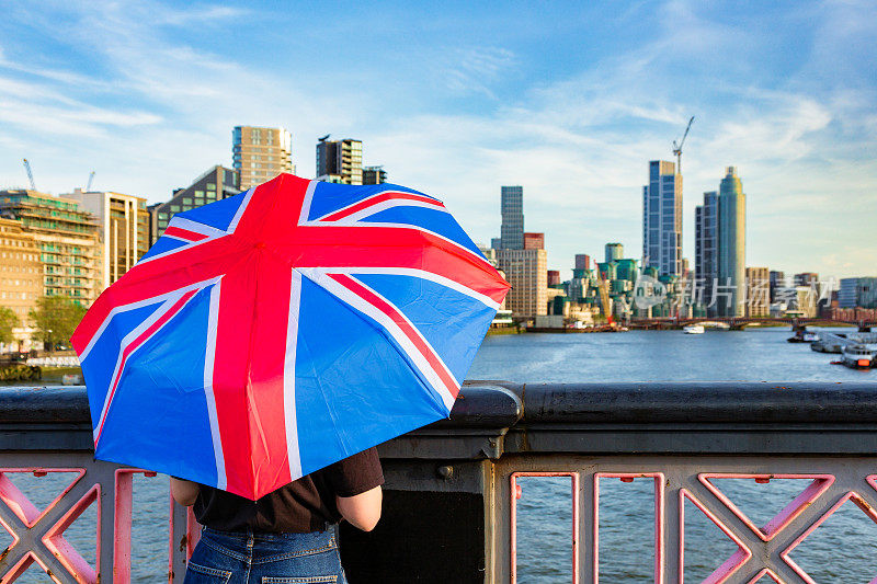 一名女子在伦敦市中心的一座桥上撑着英国国旗伞