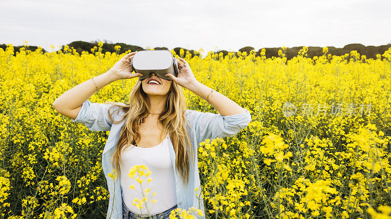 一名女子在花丛中戴着虚拟现实眼镜