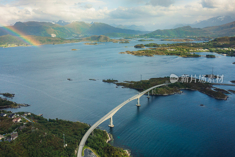 航拍的汽车行驶在挪威的岛屿和彩虹之间的现代海洋桥梁