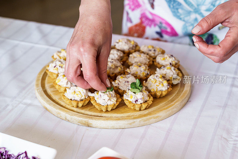 图为一名年轻女子在做点心。松饼和迷你三明治加蘑菇。