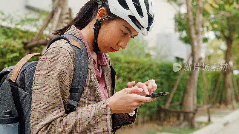 年轻的亚洲女商人使用智能手机和自行车从家里去办公室上班。业务通勤。