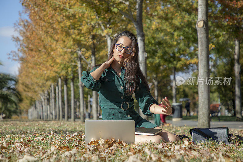 一个年轻的黑发女人在公园里摆弄她的电脑