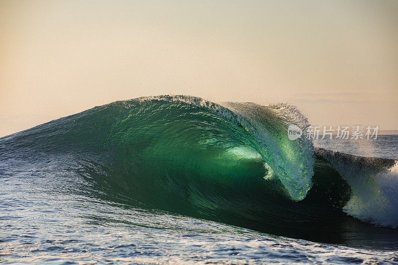 日出时，独特的海浪在金色的天空中破碎