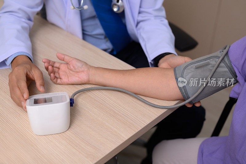 男医生在检查室测量一位老年女病人的血压。