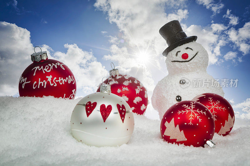 雪人在雪地里拿着圣诞树球