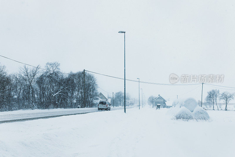 在斯堪的纳维亚小镇的冬季暴风雪中，汽车行驶在雪地上