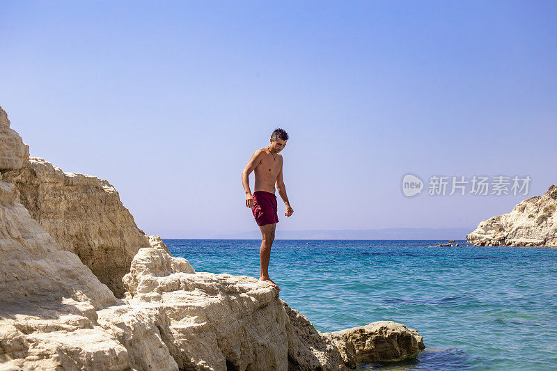 一个人站在海上的悬崖顶上