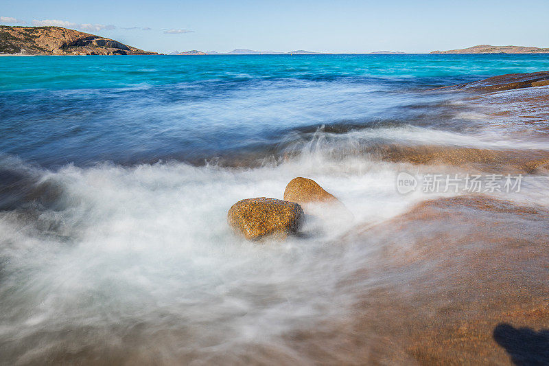 慢快门海岸场景，海水蓝色的海浪轻轻地冲刷着岩石